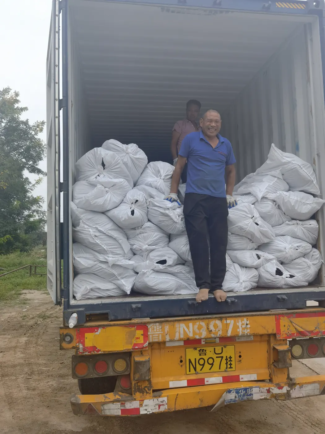 Worker loading bales of agricultural netting into a shipping container