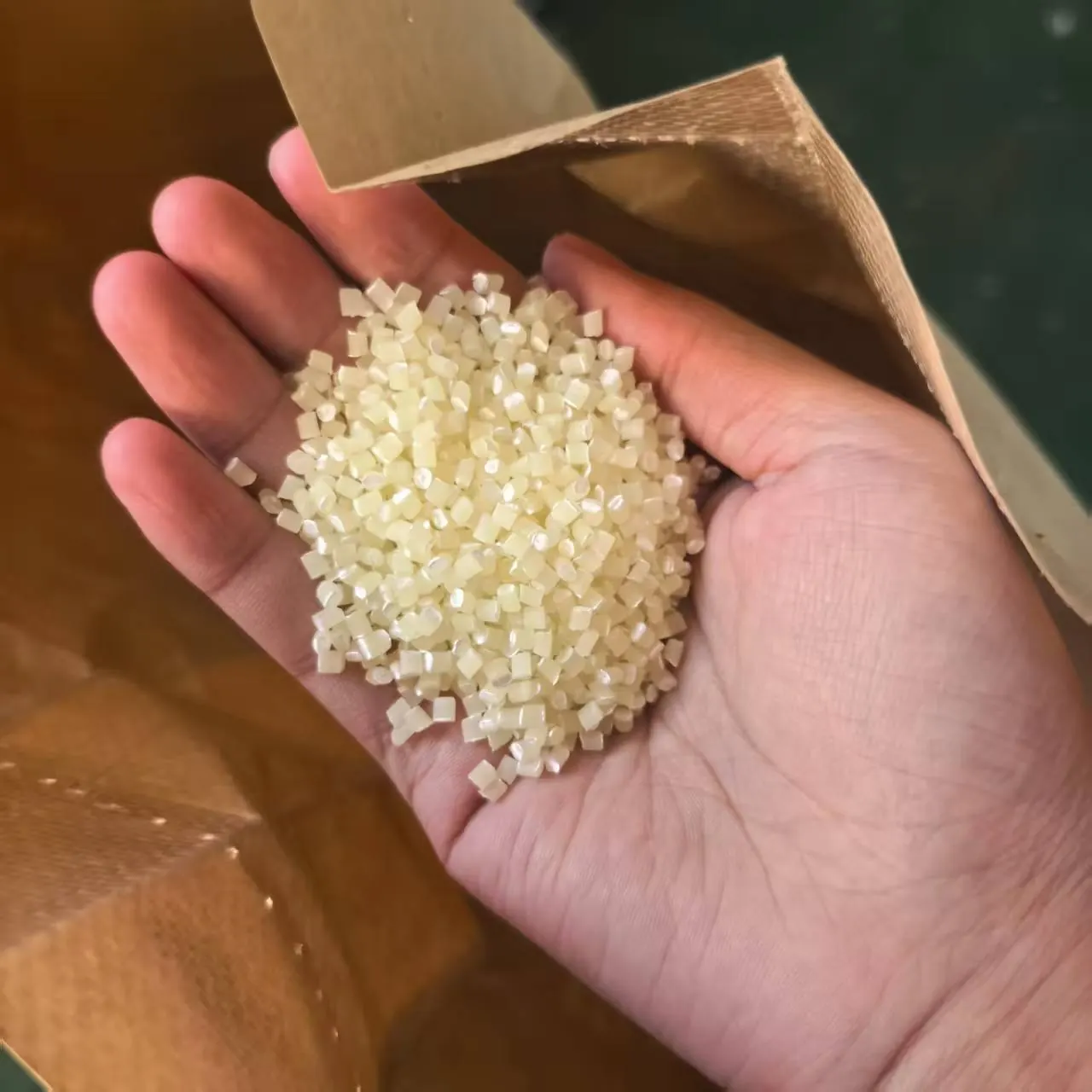 Virgin HDPE granules held above an open raw-material sack at the manufacturing plant visited by Mesh & Net